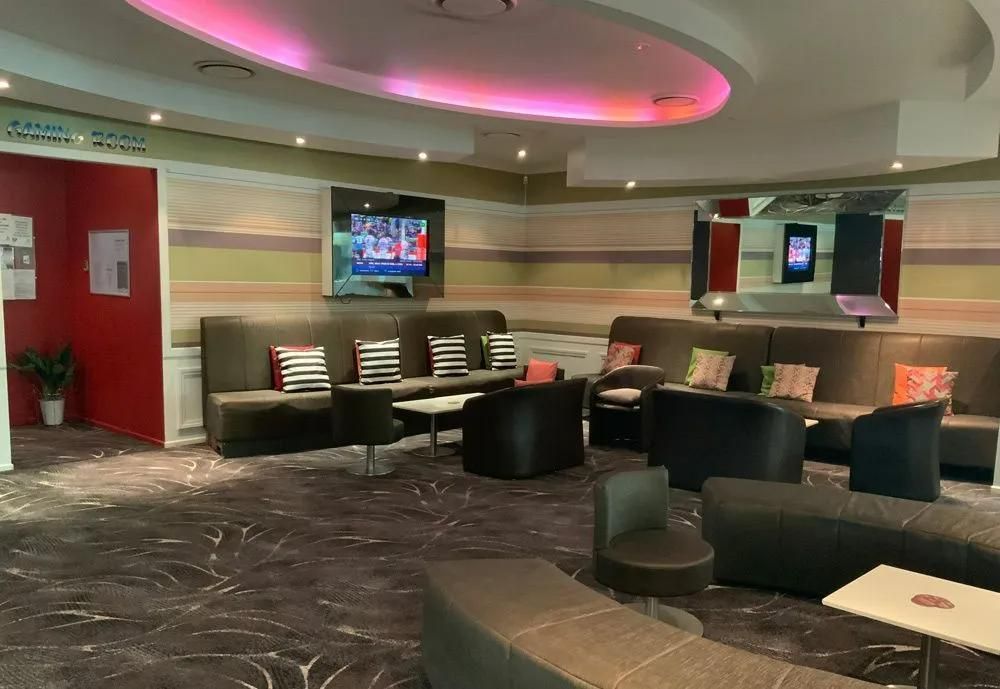 Lounge Area With Gray Sofas, Low Tables, and a Tv on the Wall — Capricorn Tavern in Taranganba, QLD