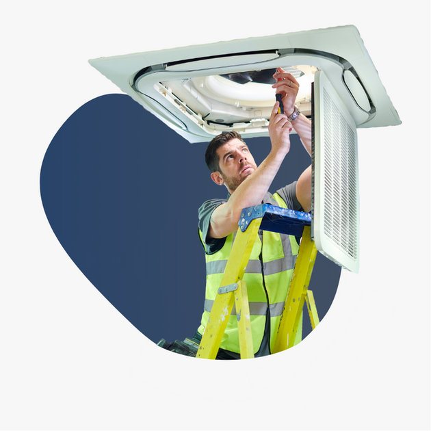 A man is standing on a ladder working on an air conditioner.