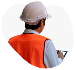 A man wearing a hard hat and an orange vest is looking at a tablet.