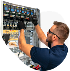 A man is working on an electrical panel in a factory.