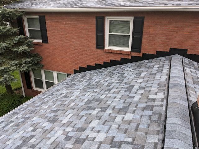 A brick house with a gray roof and black shutters.