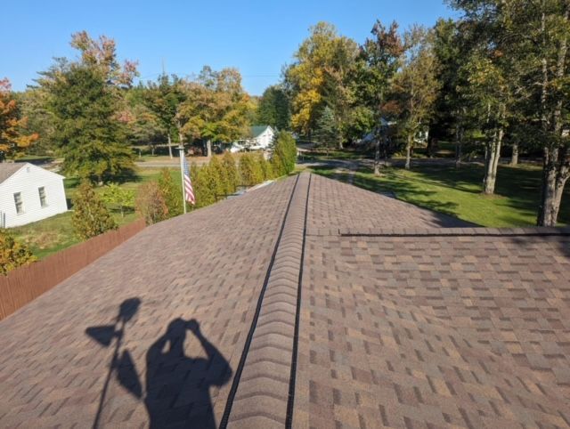 A shadow of a person is cast on the roof of a house