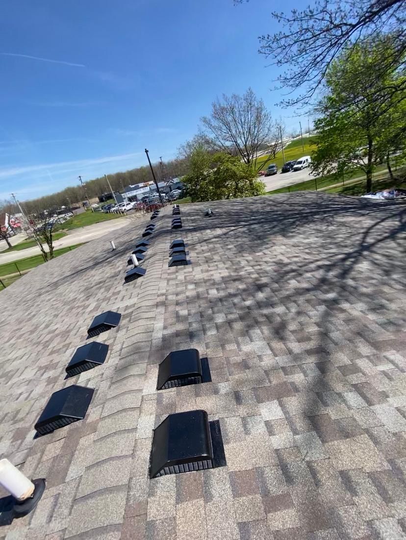 A roof with a lot of vents on it and trees in the background.