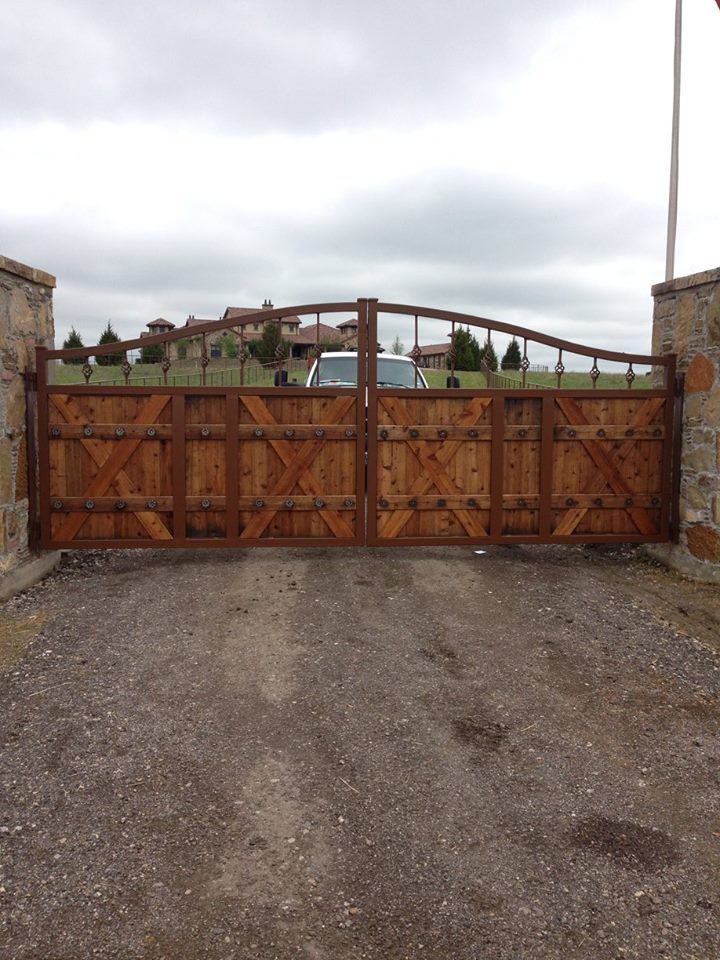 A wooden gate is sitting in the middle of a gravel road.