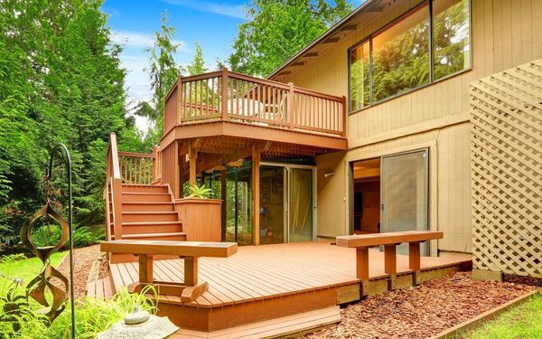 The back of a house with a large wooden deck and stairs.