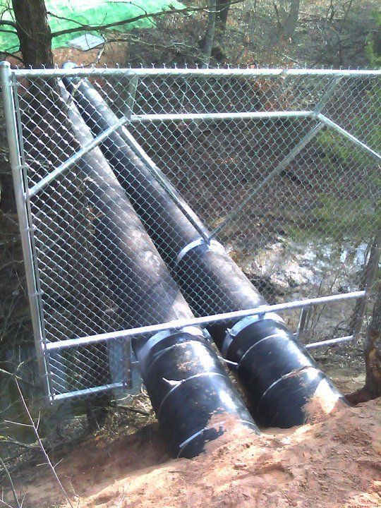 Two black pipes are behind a chain link fence