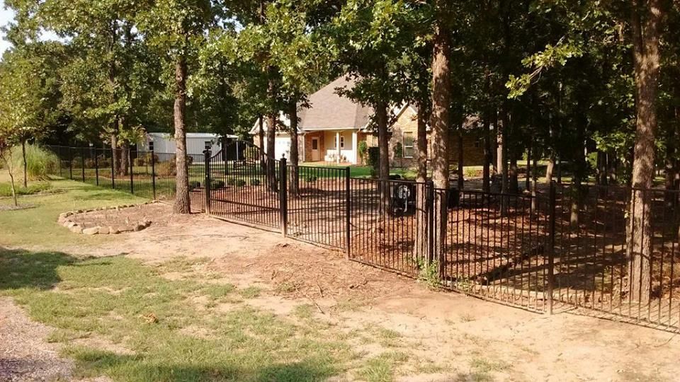 A house is behind a fence with trees in the background.