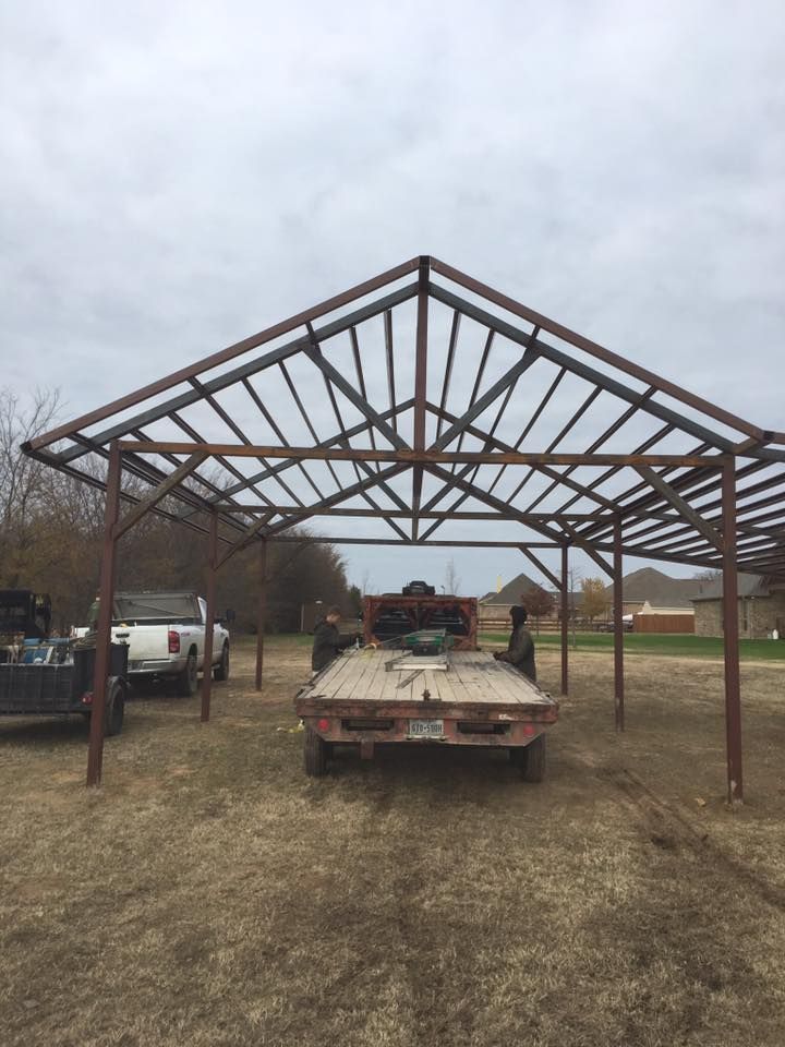 A truck is parked under a metal structure in a field