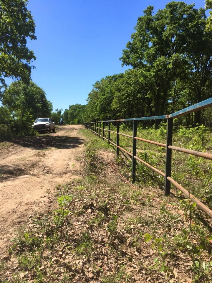 A truck is parked on the side of a dirt road next to a fence.