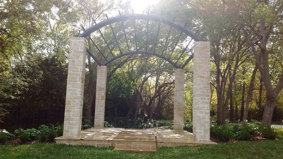 There is a gazebo in the middle of a park surrounded by trees.
