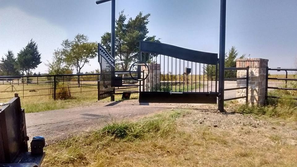 A gate is open in a field with trees in the background