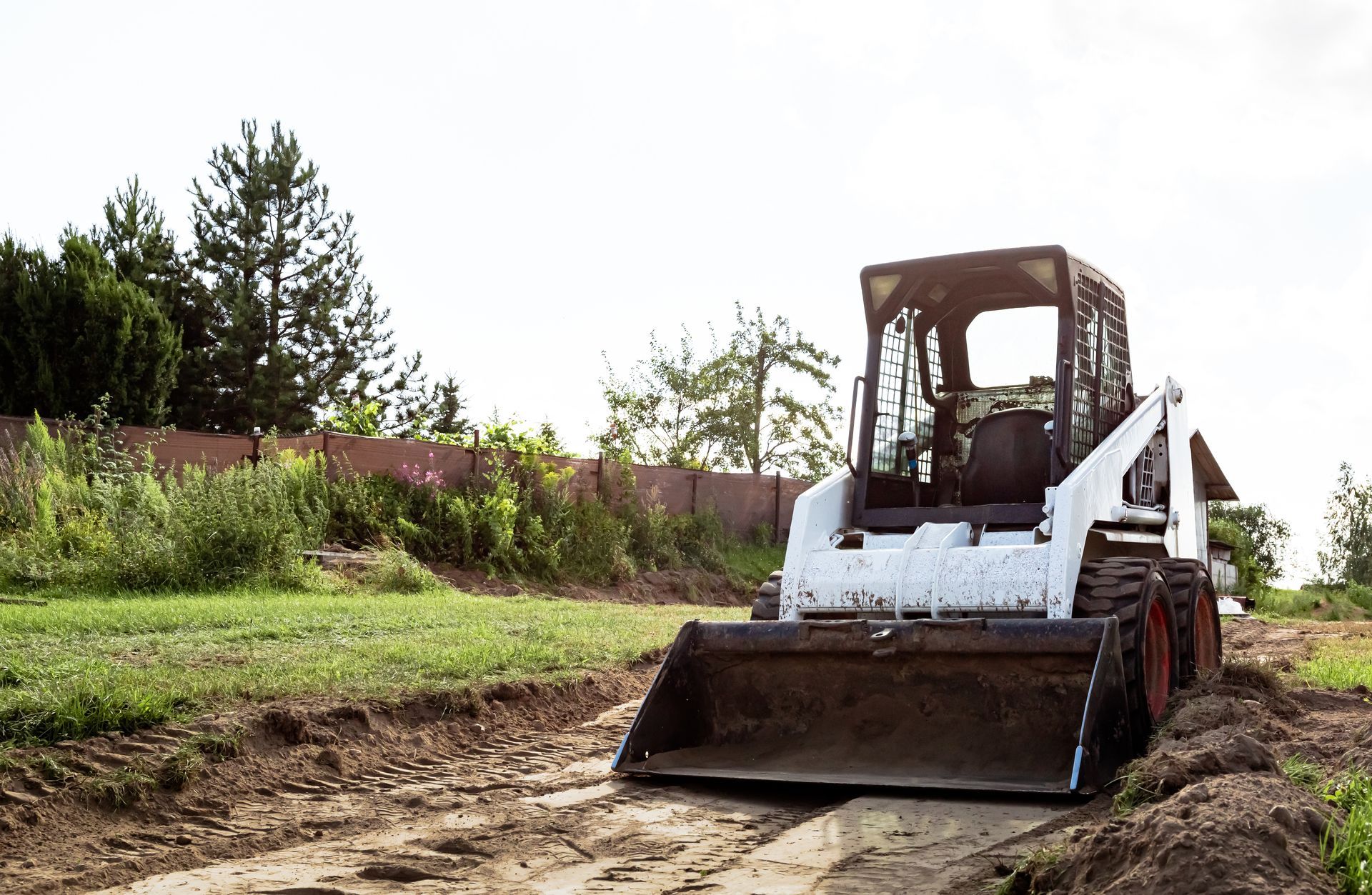 A bulldozer is driving down a dirt road in a field.