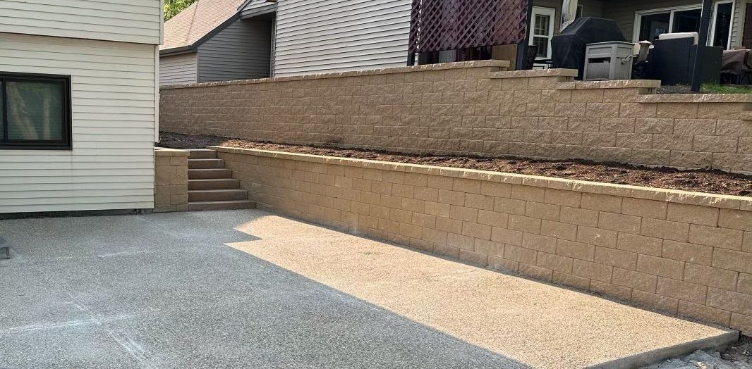 A house with a stone wall and stairs in front of it.