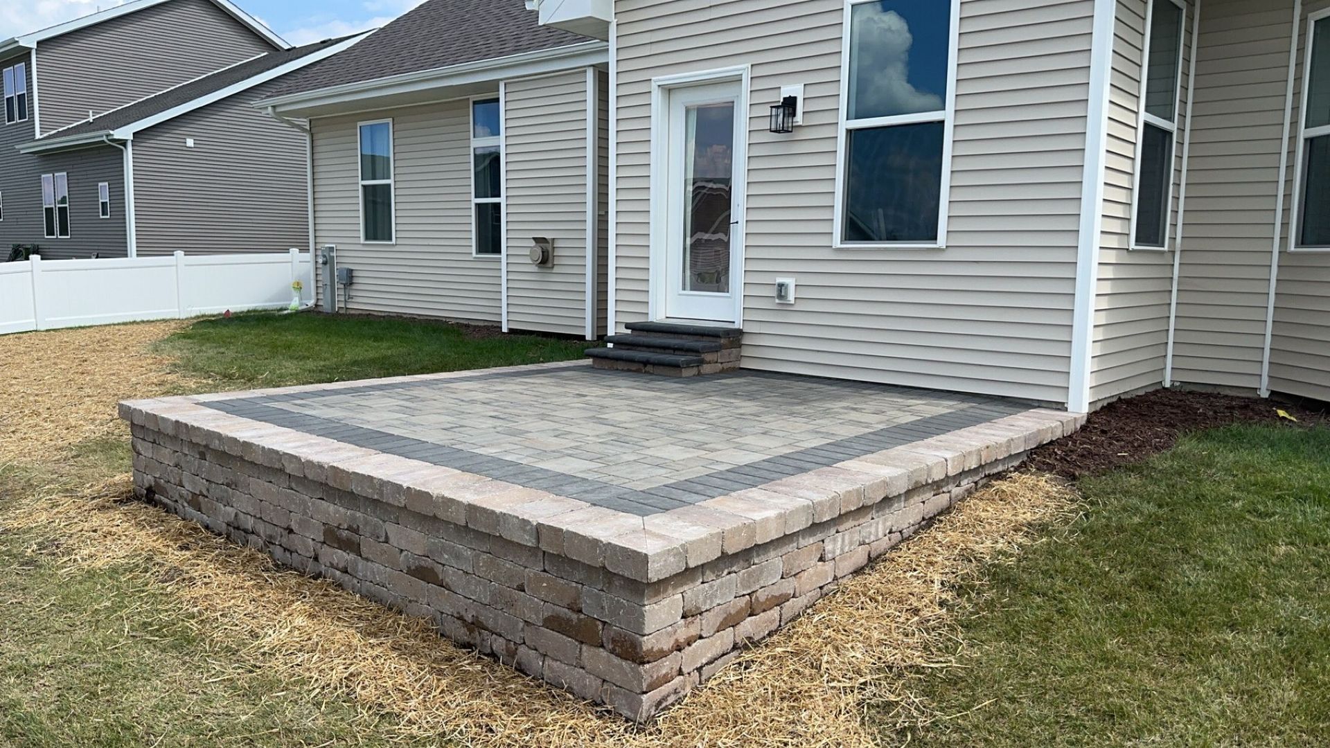 A large house with a lush green lawn and a stone walkway leading to it.
