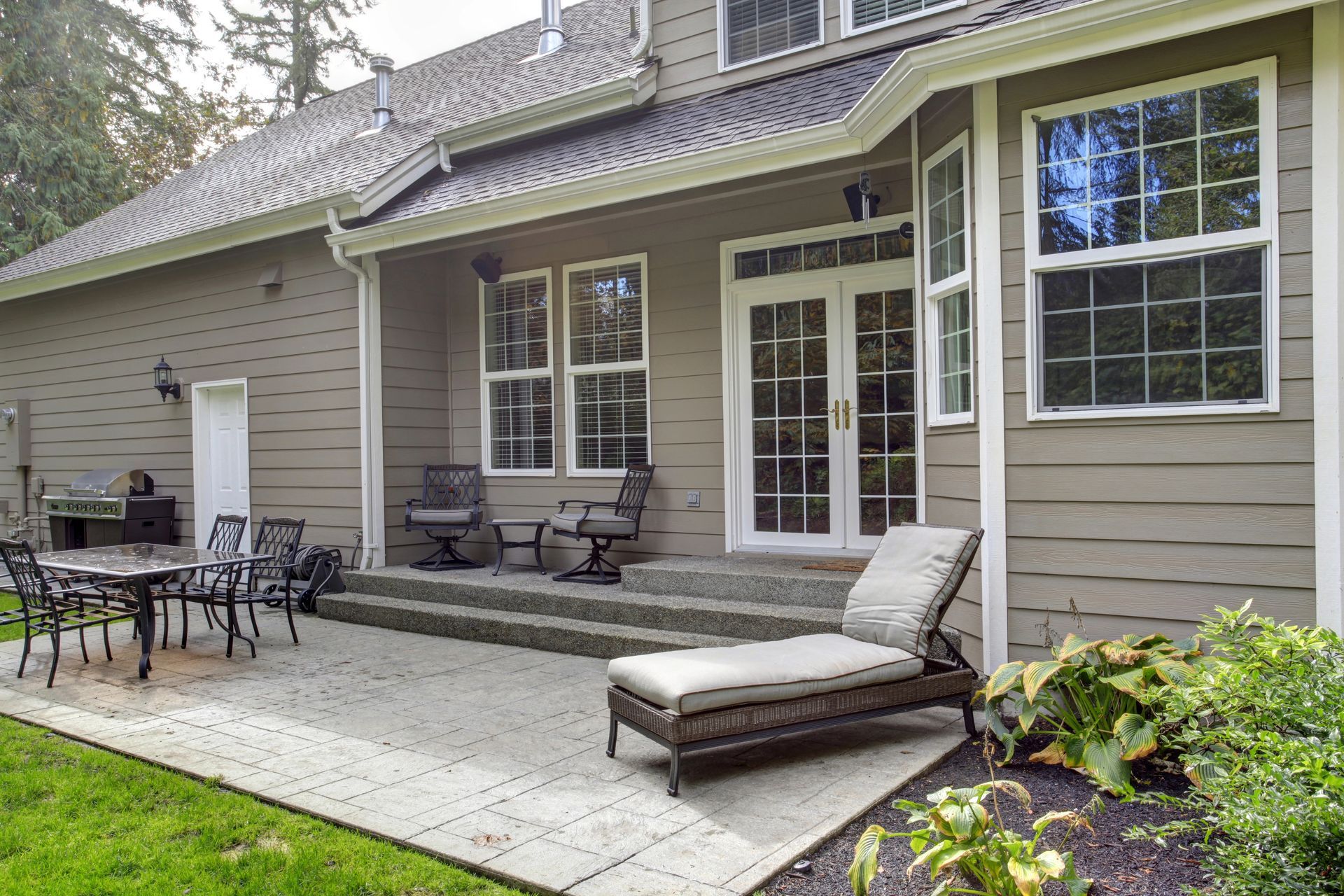 A large house with a patio and chairs in front of it.