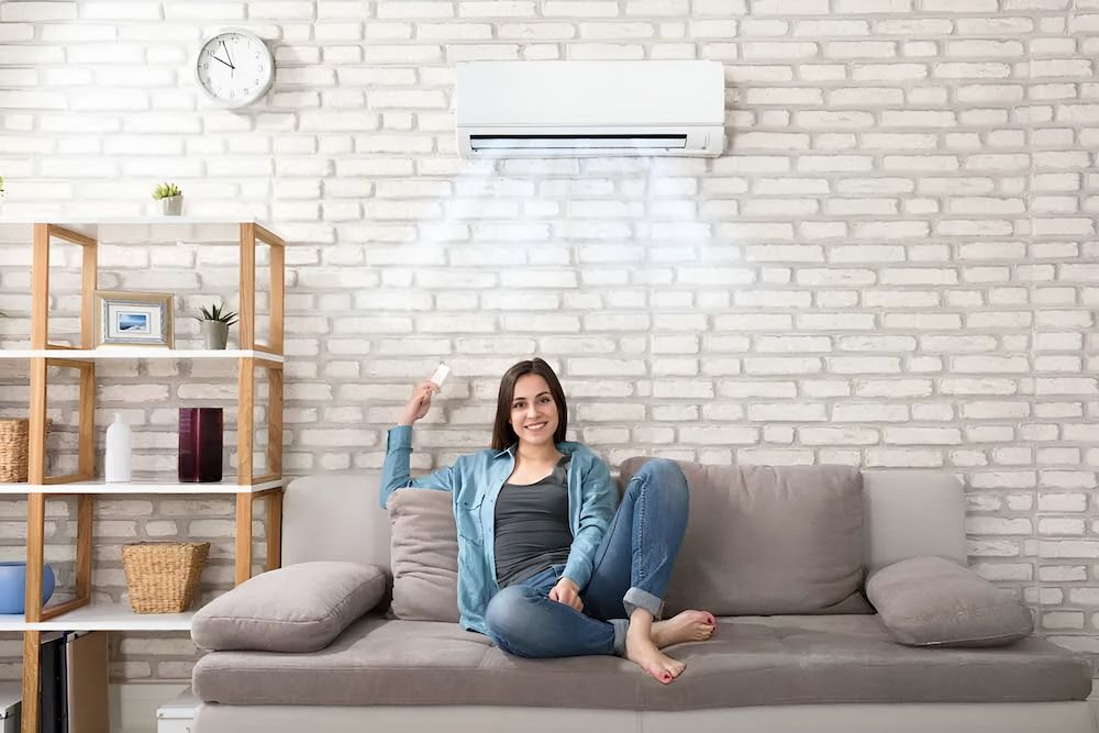 Woman on Sofa, Holding Remote, Enjoying Air Conditioning — EcoAir Conditioning in Coconut Grove, NT