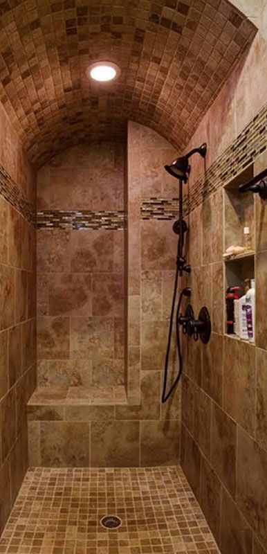 A tiled walk-in shower with a curved ceiling, a built-in bench, and black fixtures.