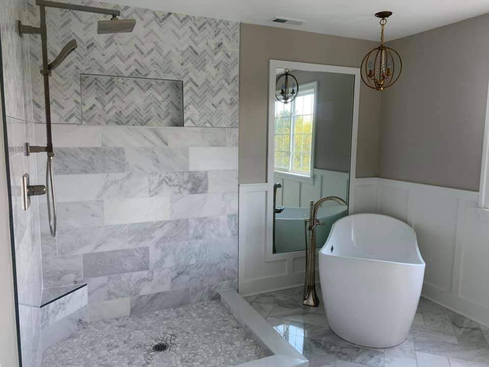 Luxurious bathroom with marble tile shower, freestanding tub, and pendant lighting.