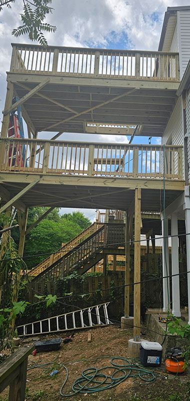 Multi-level wooden deck attached to a house with stairs leading down to the yard.