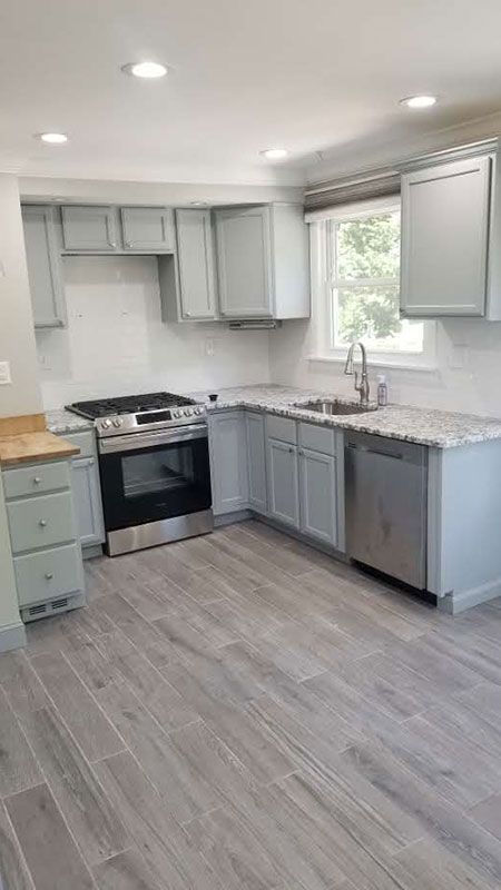 Gray kitchen with light cabinets, stainless steel appliances, and gray flooring.