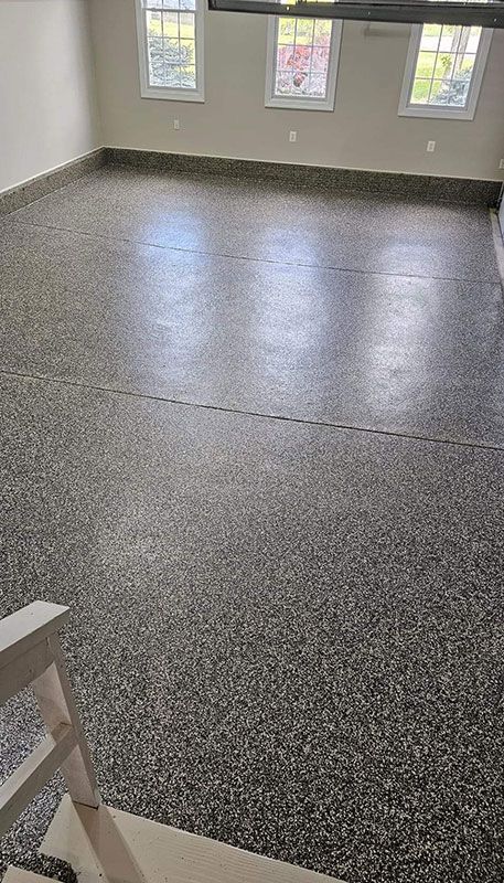 Gray speckled epoxy flooring in a room with three windows.