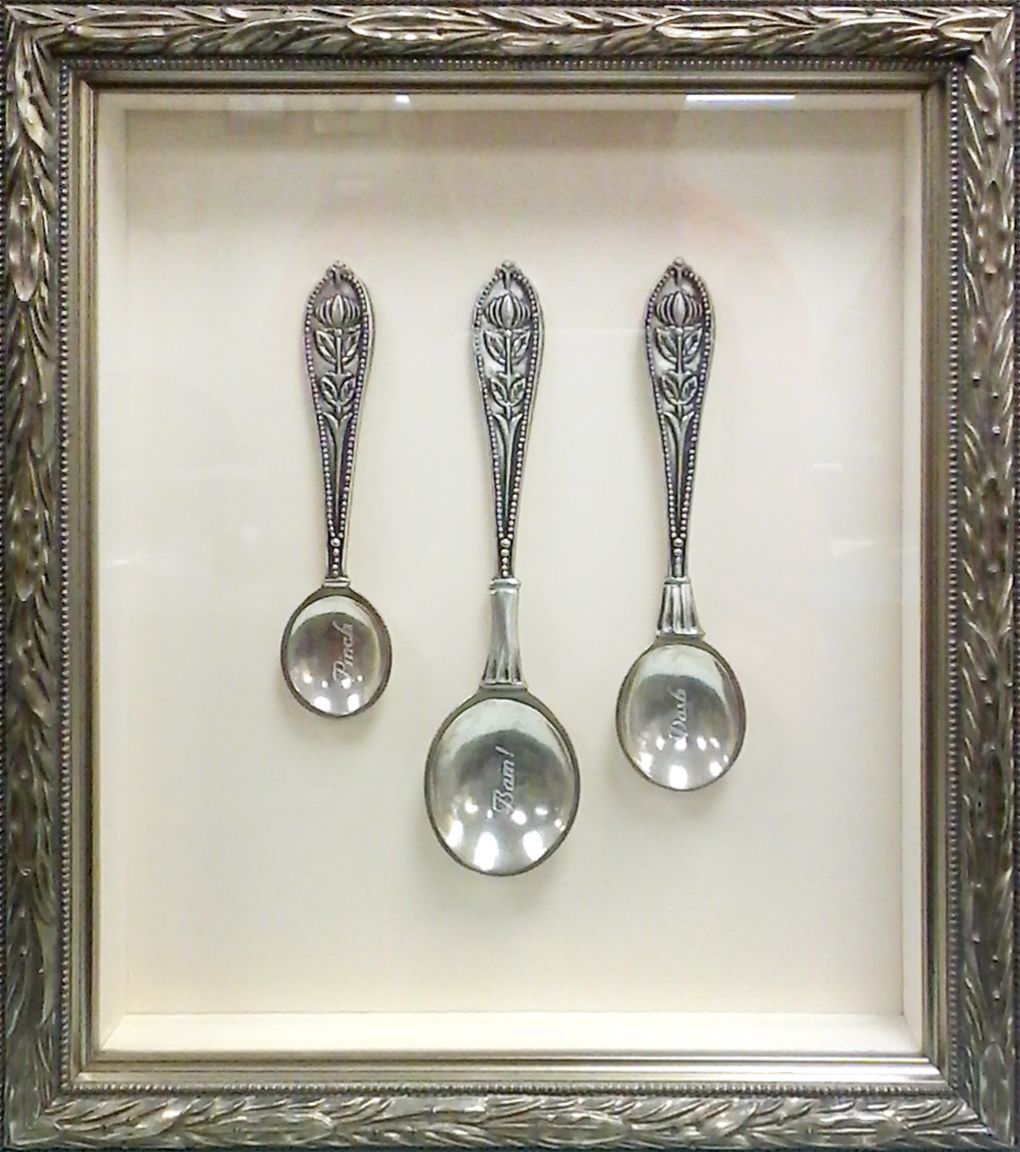 Three silver spoons in a silver frame on a white background