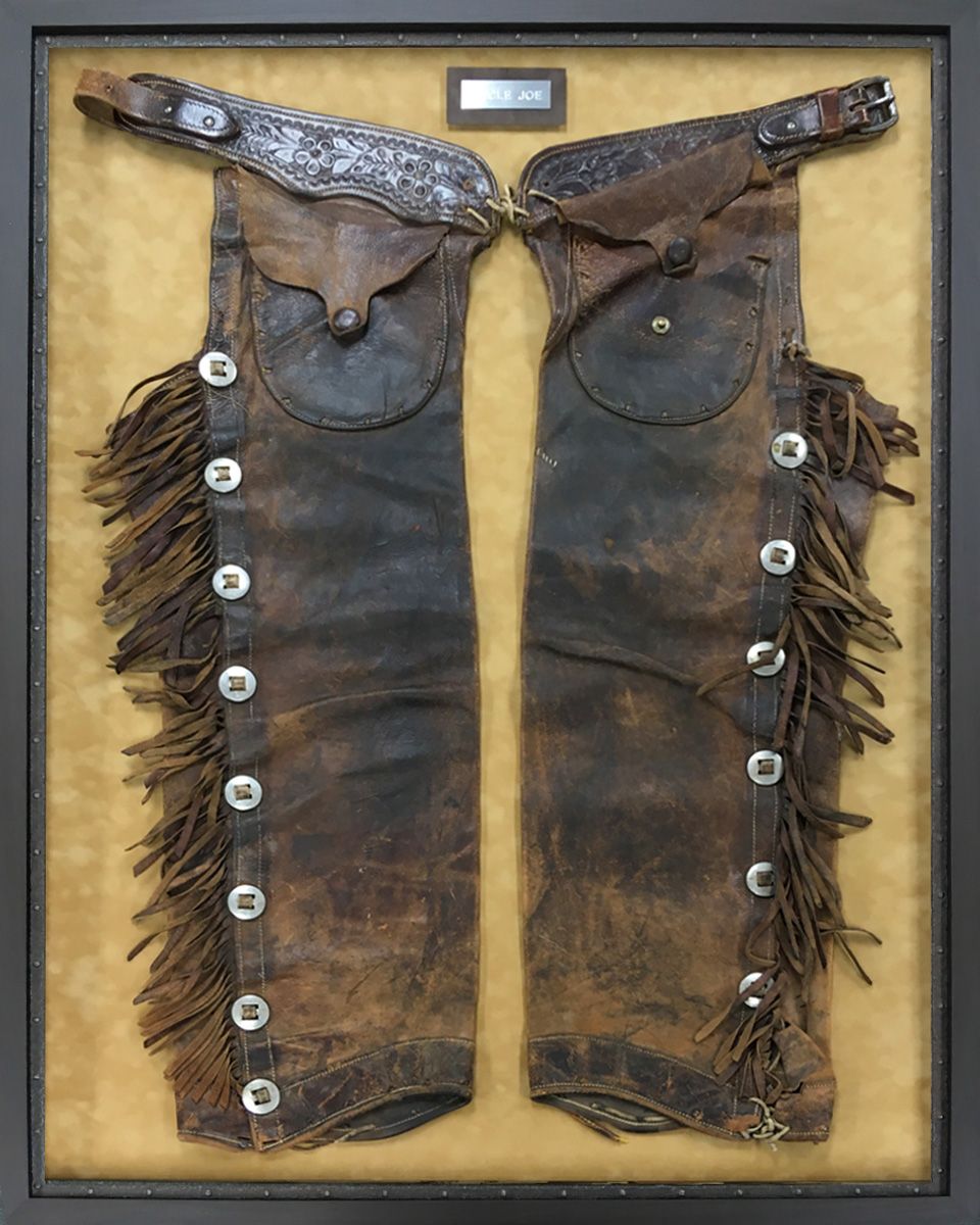 A pair of brown leather chaps in a frame
