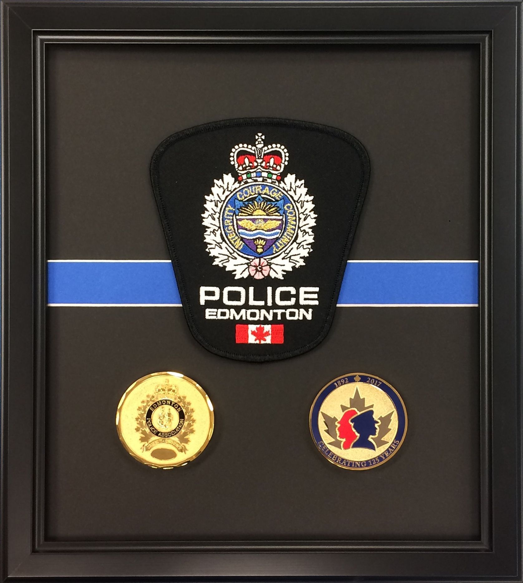 A framed display of a police patch and two coins
