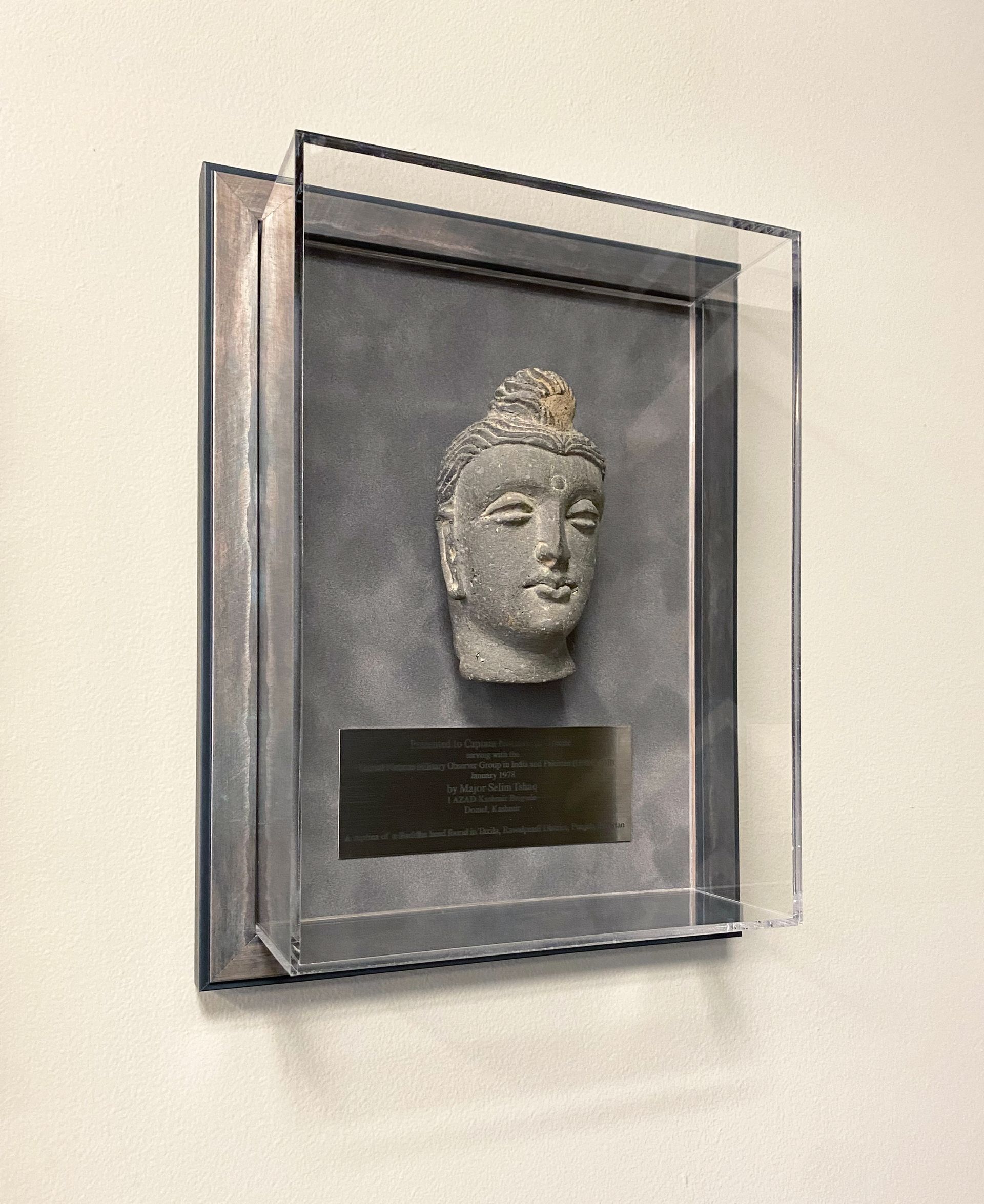 A framed sculpture with an inscription plaque underneath