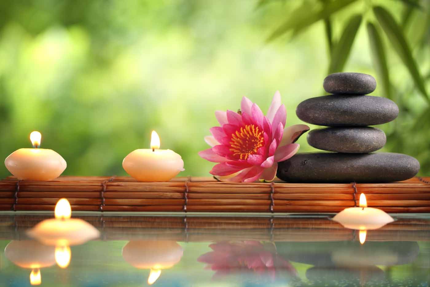 a bamboo stand holding candles and stones 