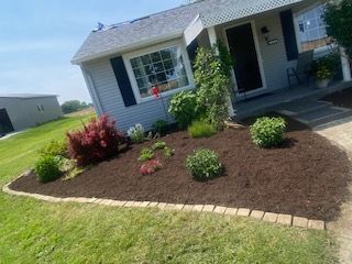 Small house with landscaped flower bed and brown mulch.