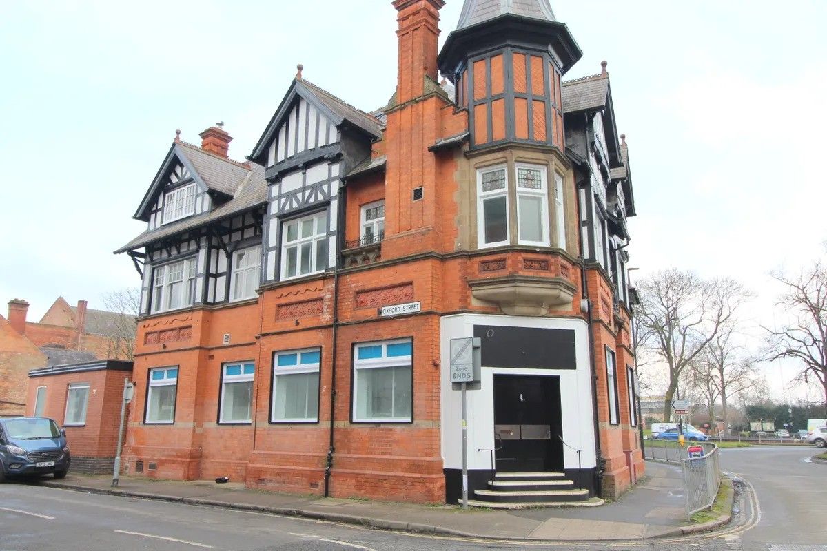 A large brick building is sitting on the corner of a street.