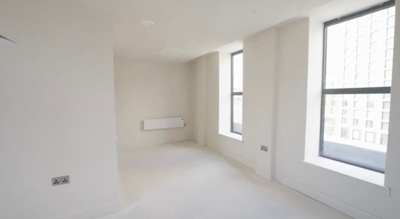 An empty room with white walls and two windows.