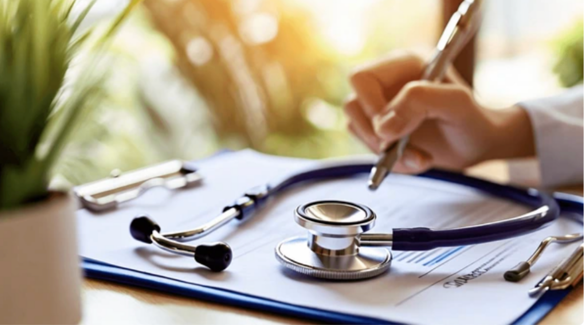 A smiling doctor in a lab coat with a stethoscope around his neck.