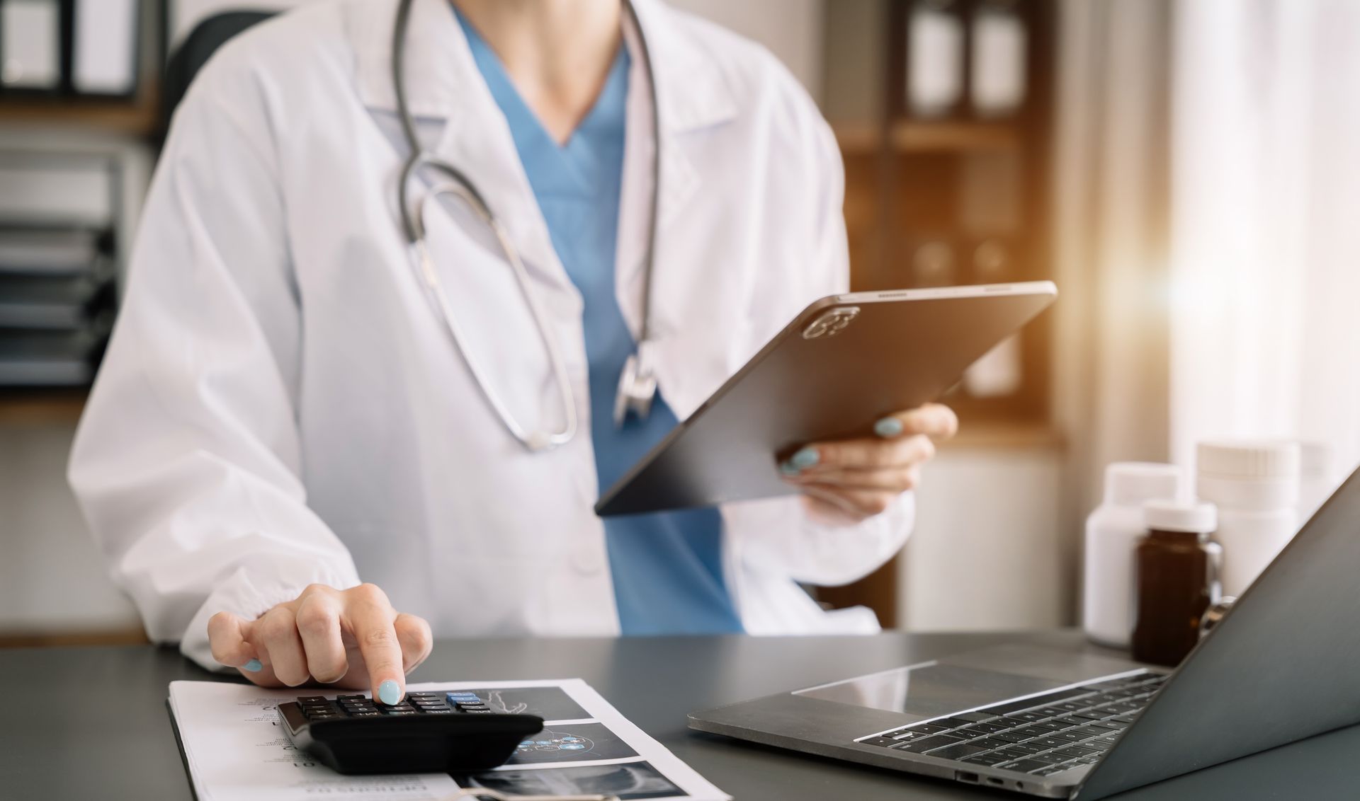 A smiling doctor in a lab coat with a stethoscope around his neck.