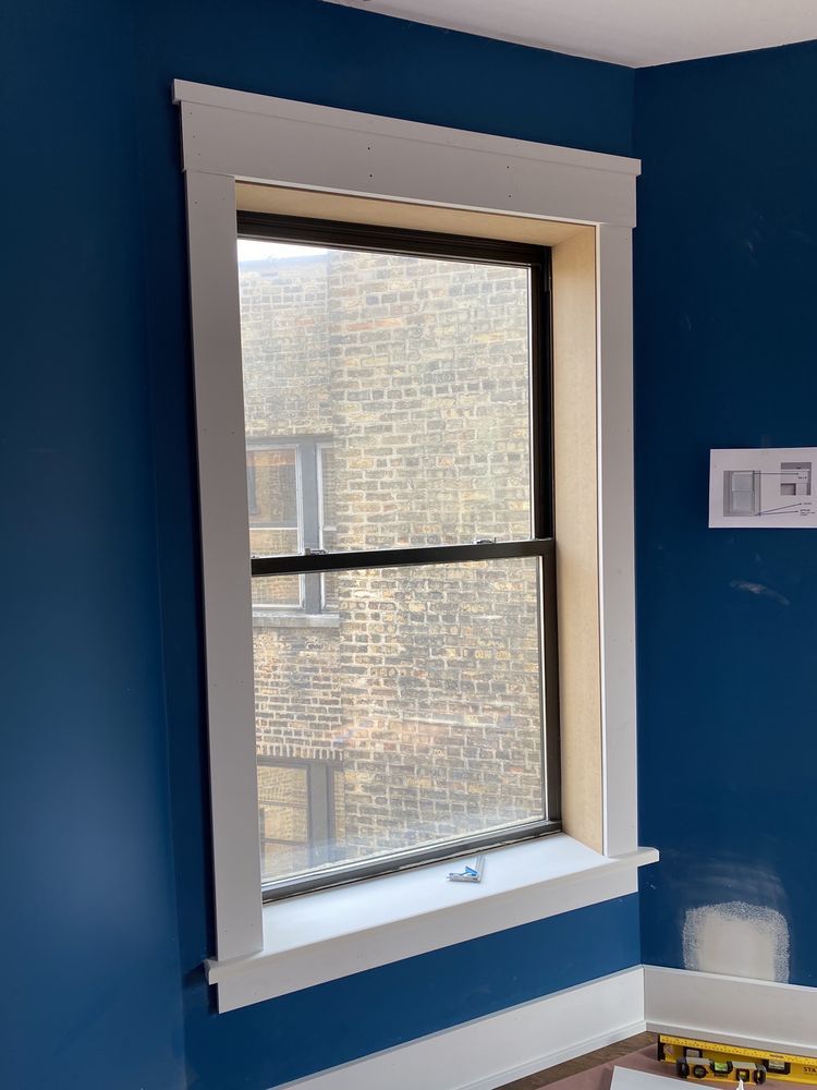 Window with white trim and blue walls, overlooking a brick building.