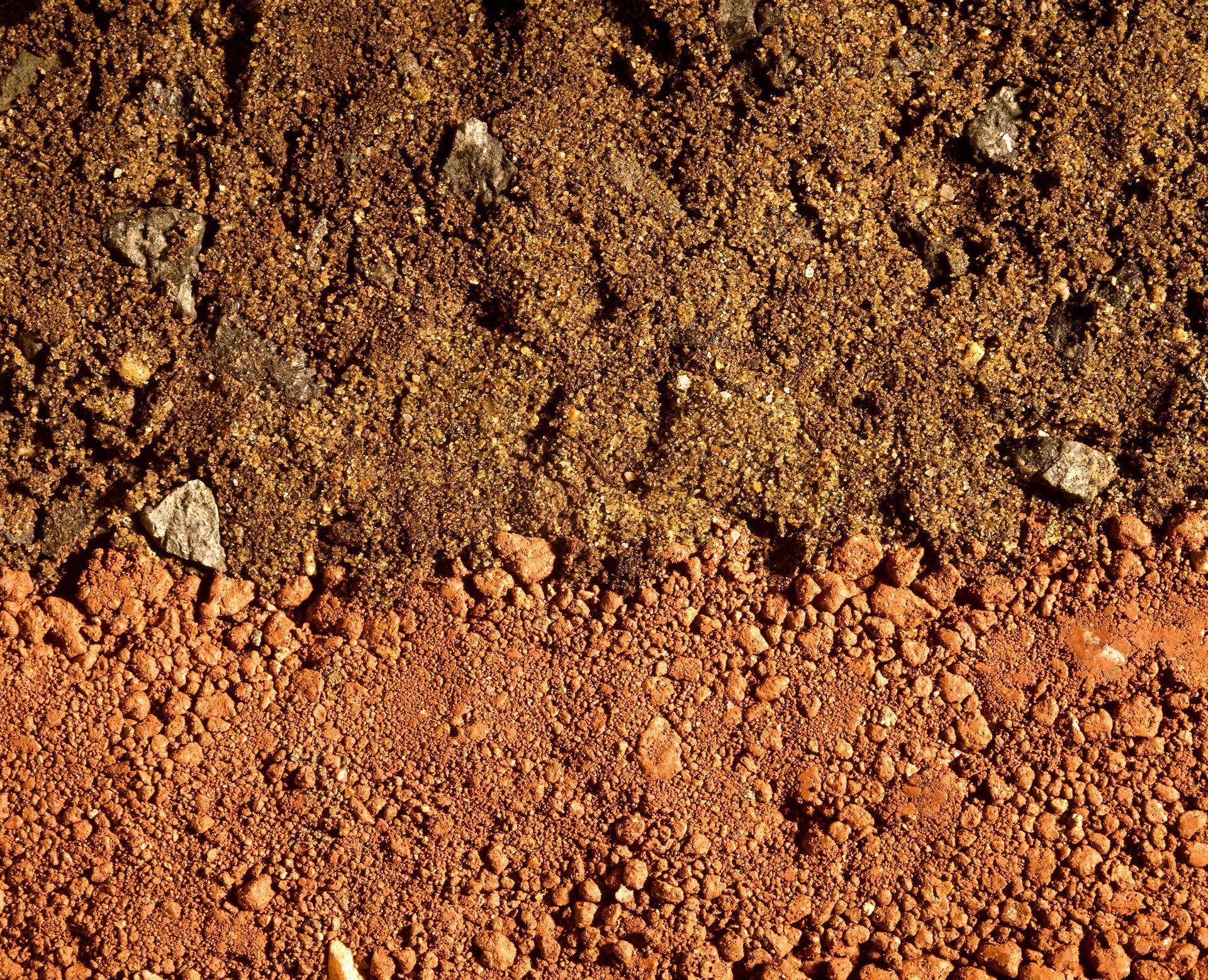 Cross-section of soil, showing layers of dark brown topsoil over red clay.