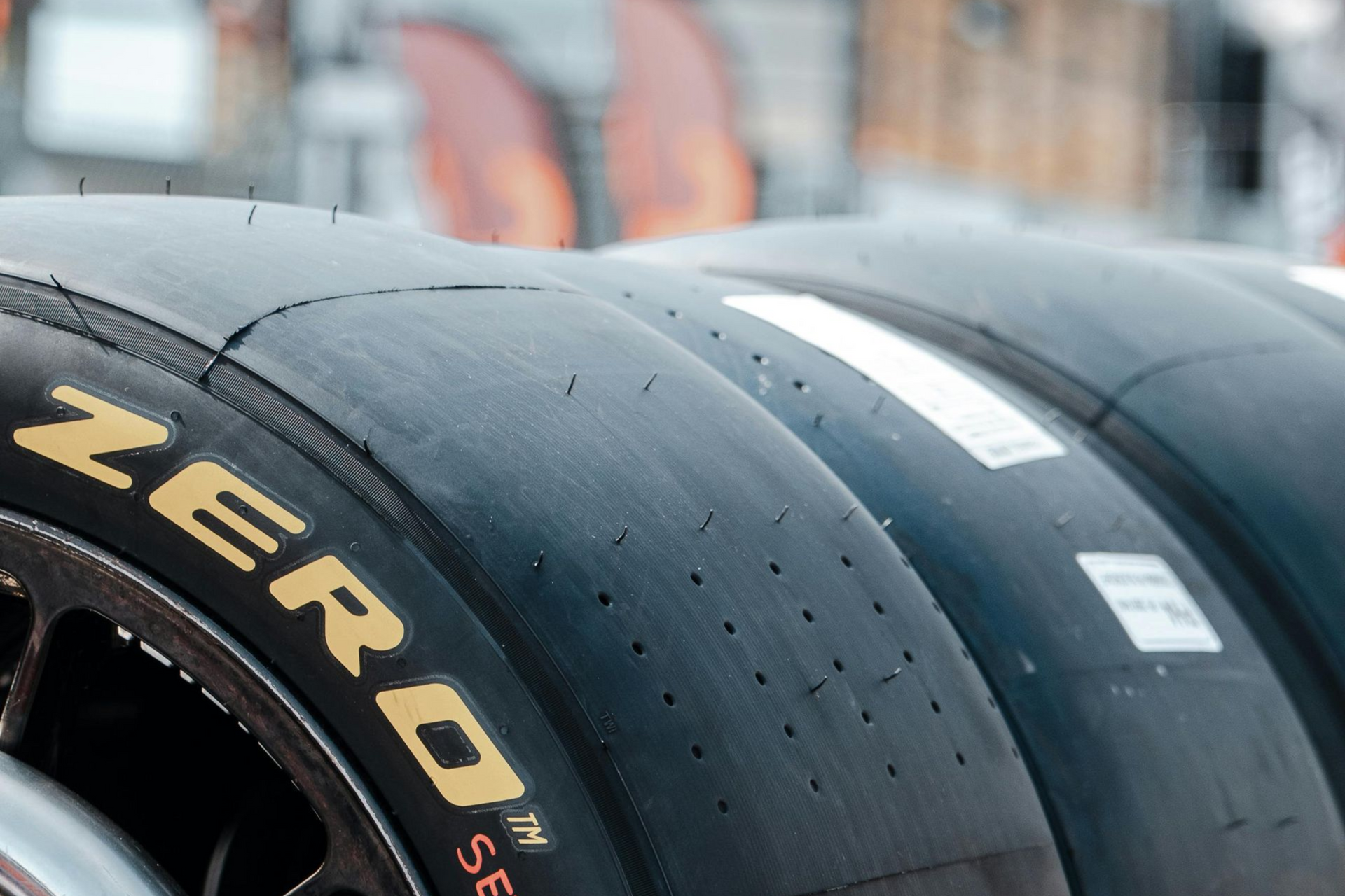 Black Pirelli racing tires stacked on a metal rack, with 