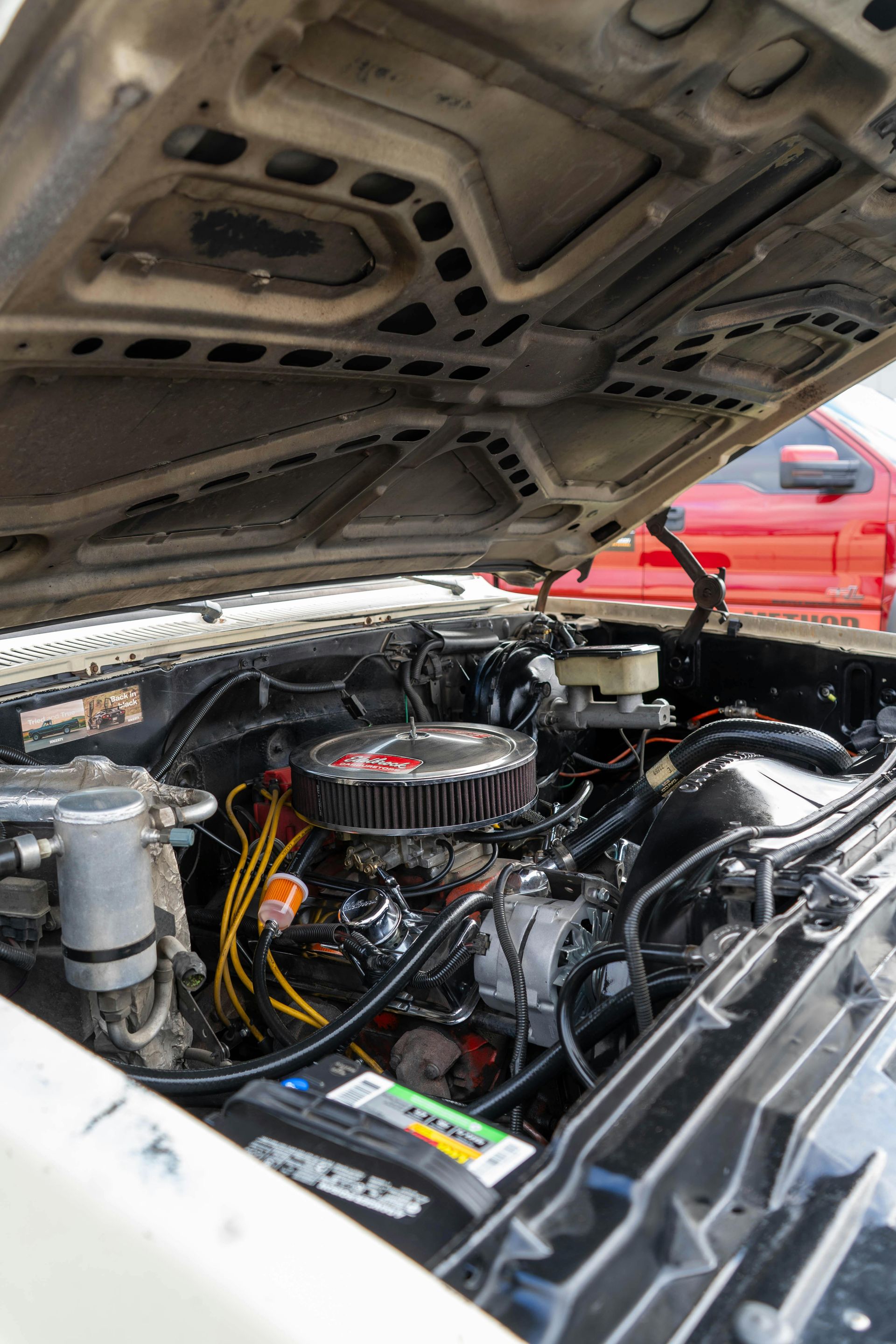 Row of black tires with price tags on a red metal rack in a store.