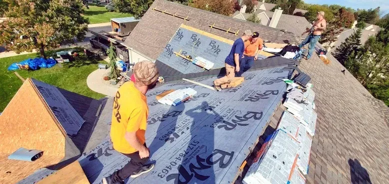 Roofers installing roofing material on a residential roof.