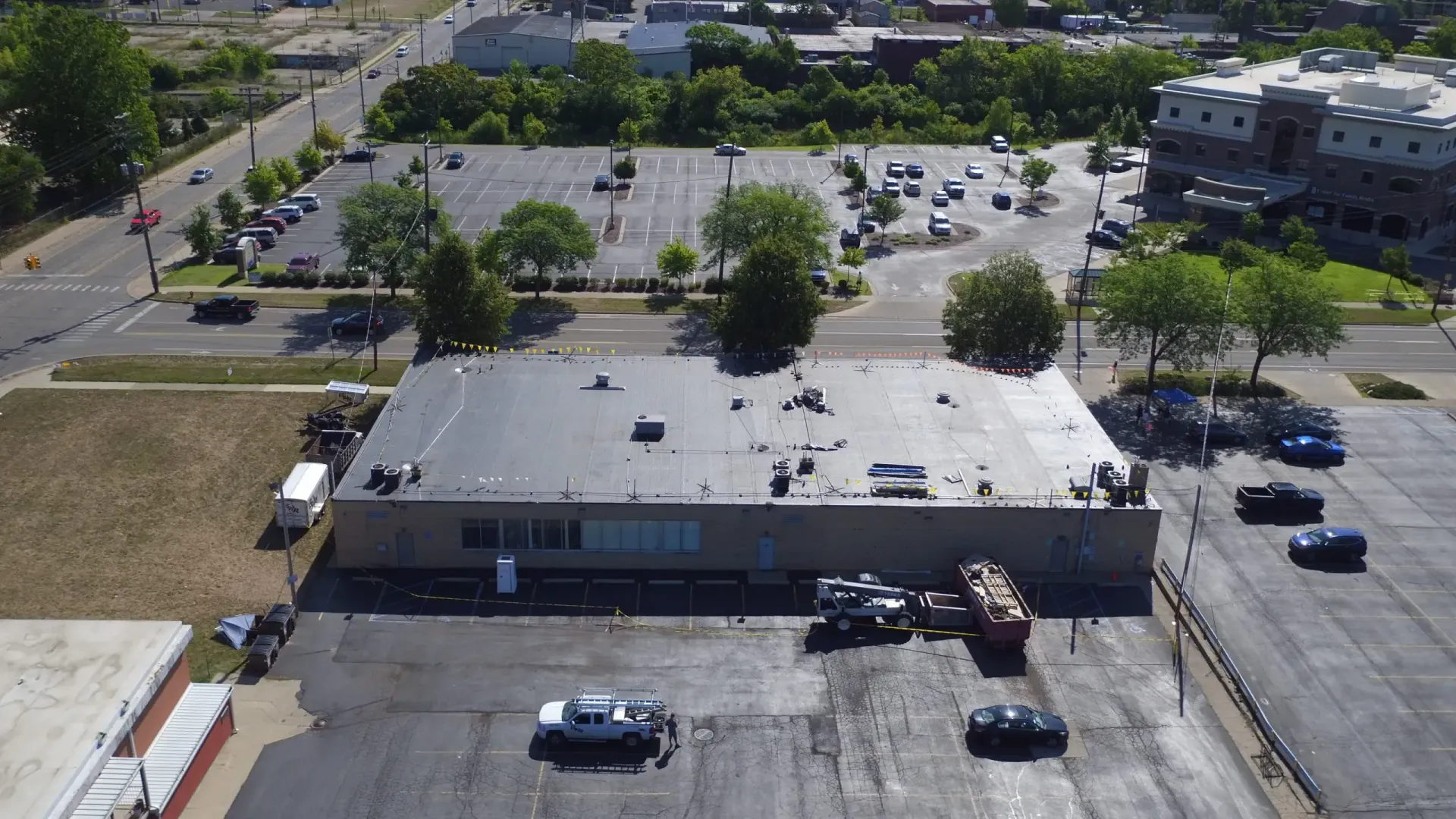 Aerial view of a single-story building with a flat roof, surrounded by parking lots and roads.