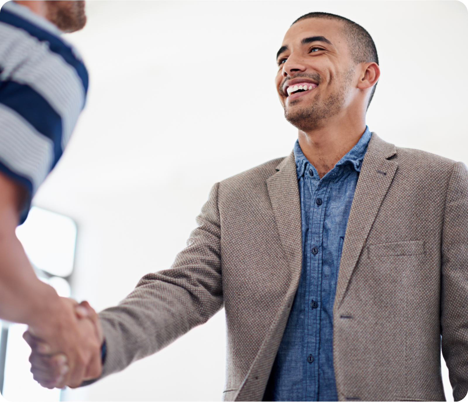 A man in a suit is shaking hands with another man in a striped shirt.