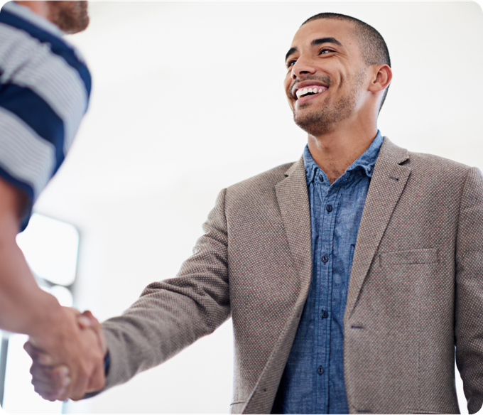 A man in a suit is shaking hands with another man in a striped shirt.