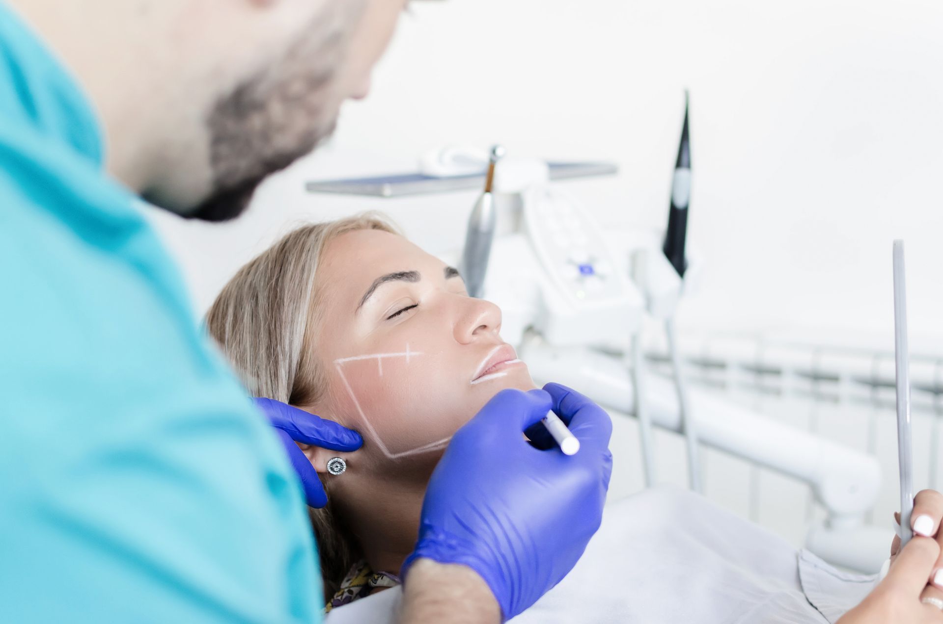 A dentist contouring a patient's face with white markings at a teeth and skin medical spa.