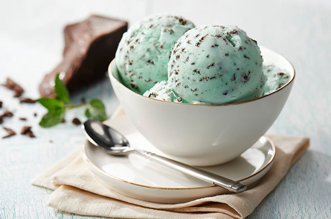 A bowl of mint chocolate chip ice cream with a spoon in it