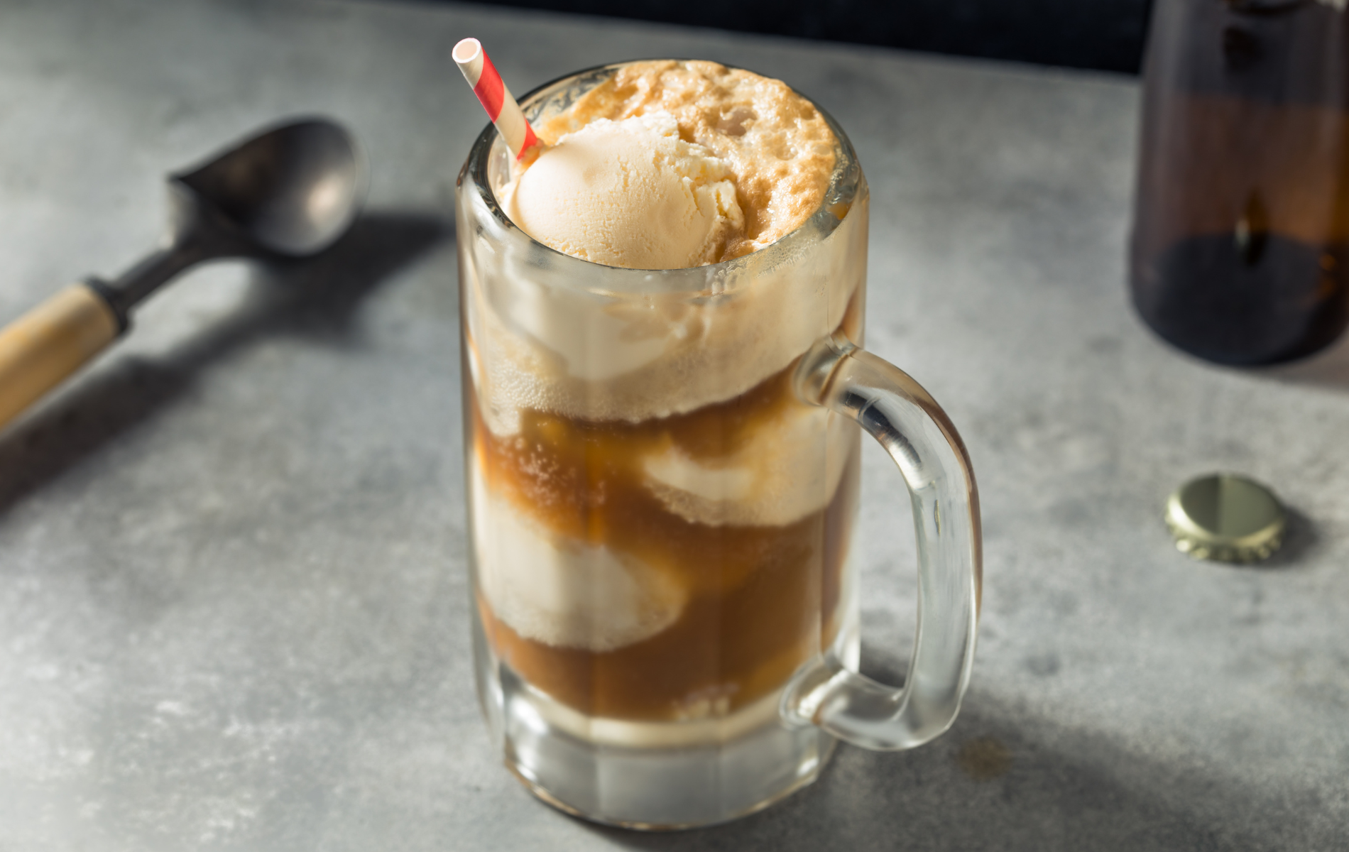 A glass of beer float with ice cream and a straw.
