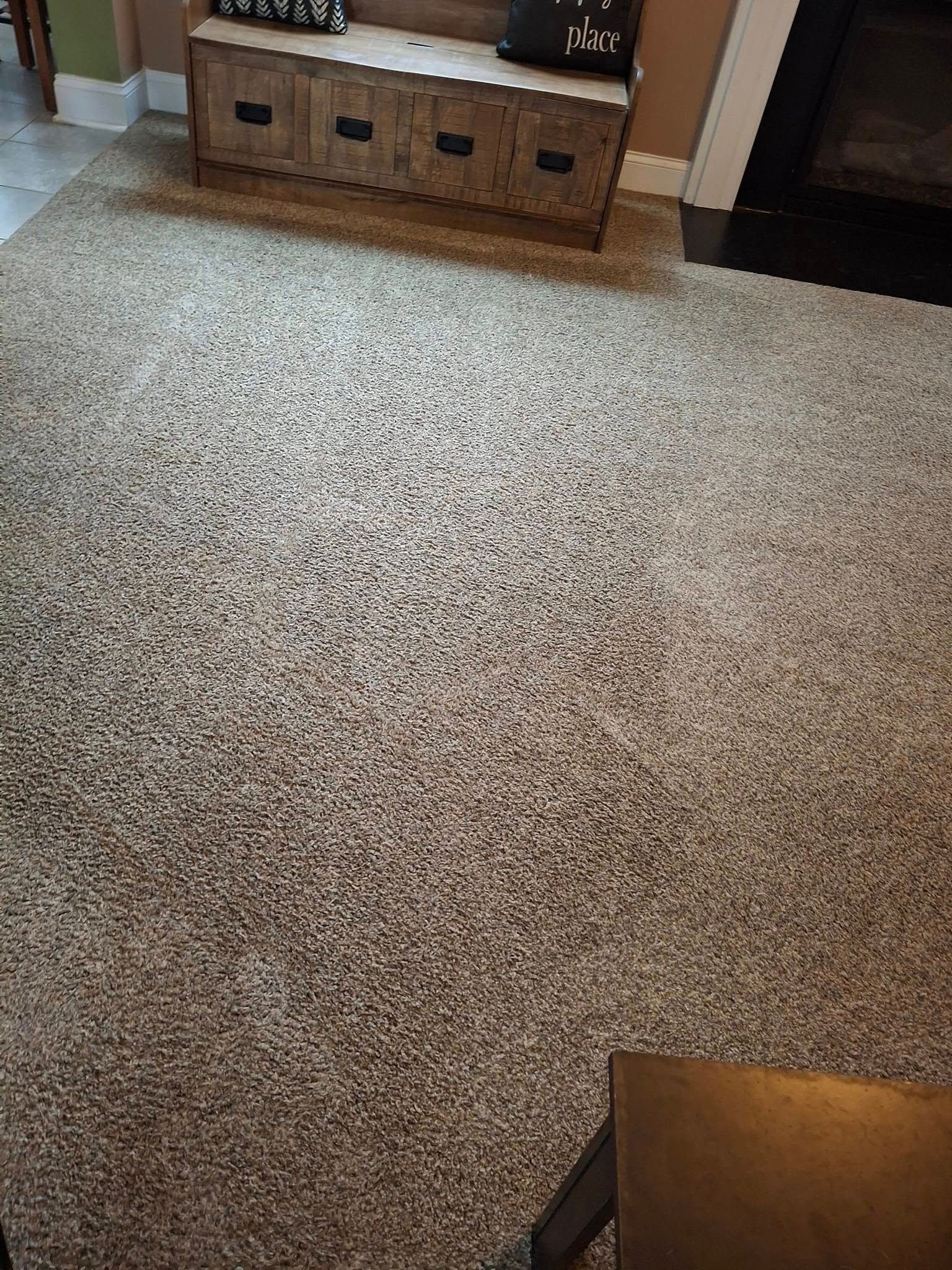 Brown speckled carpeted floor with wooden bench, and fireplace.