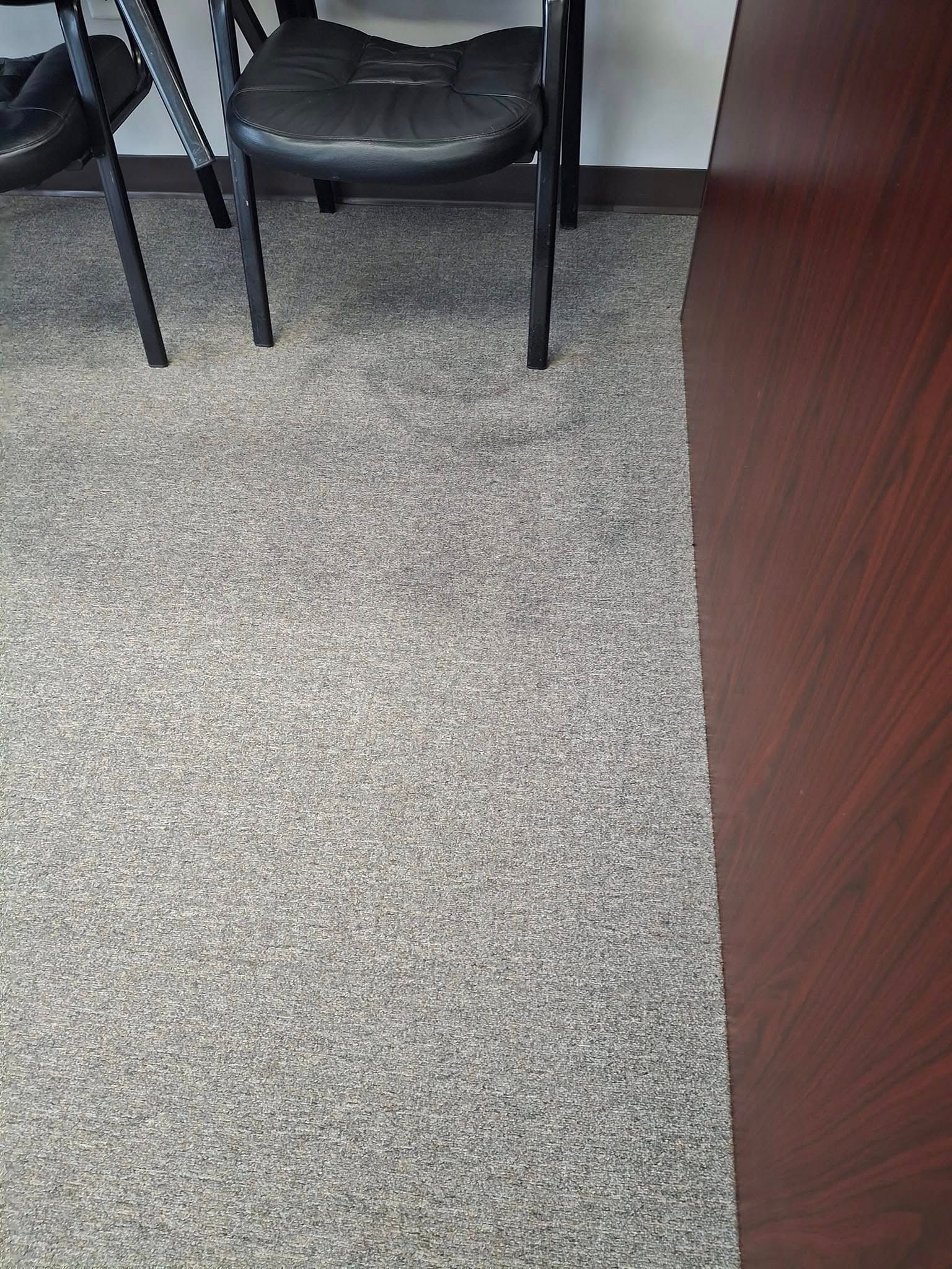 Gray carpeted floor next to a dark wood cabinet. Black chair legs in the background.