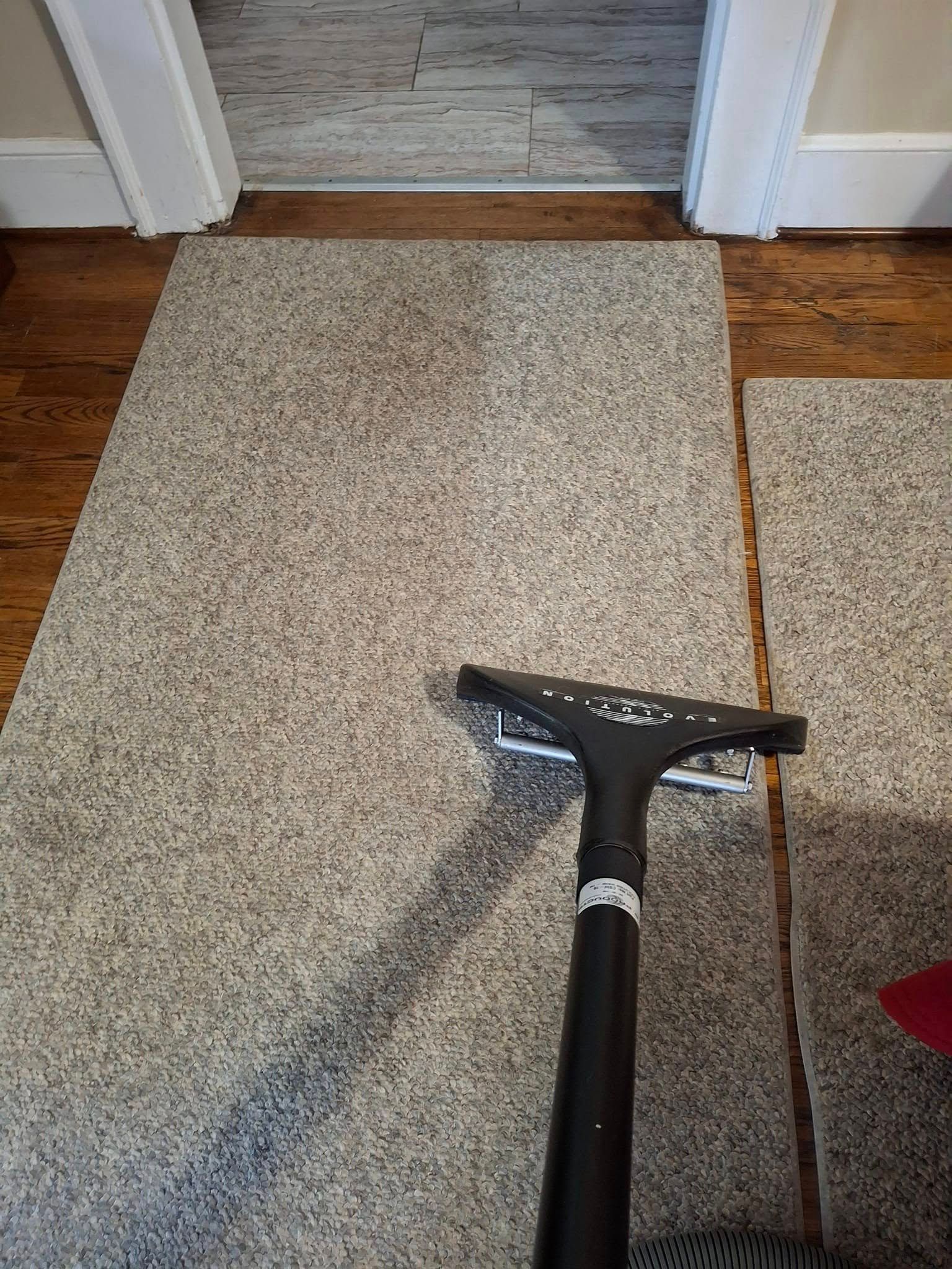 Vacuum cleaner on light gray carpet, doorway in background.
