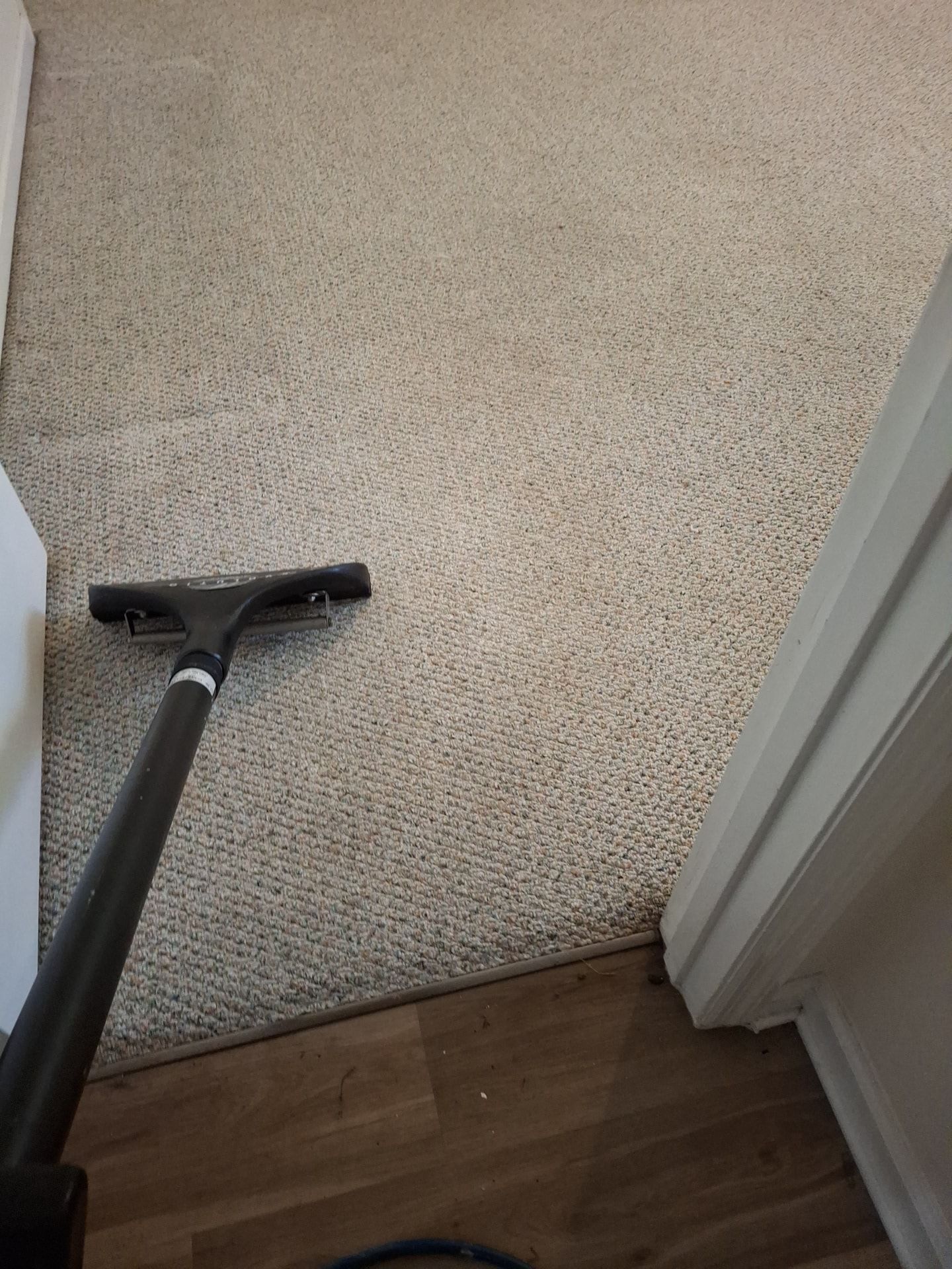 A carpeted area is being cleaned with a vacuum cleaner.